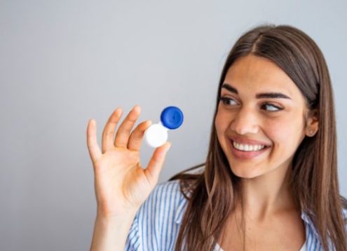 Happy girl holding a contact lens case in her hand.