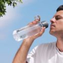 Illustration of a person staying cool under a shaded tree on a sunny day, how to prevent heat stroke