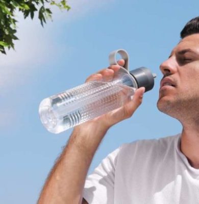 Illustration of a person staying cool under a shaded tree on a sunny day, how to prevent heat stroke