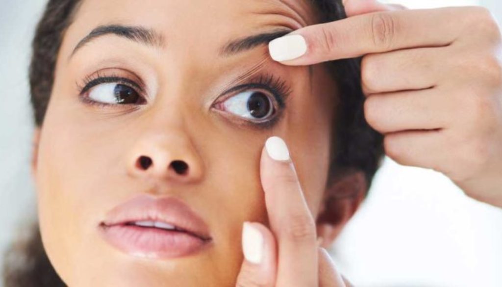 A person holding a soft contact lens, demonstrating proper soft contact lens fitting.